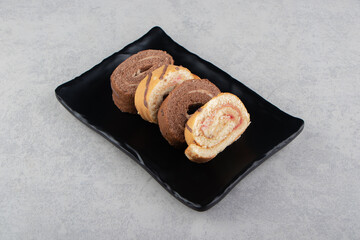 Tasty roll cake on the board , on the marble background