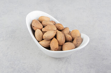 Almonds in the white bowl, on the marble background