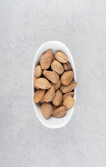 Almonds in the white bowl, on the marble background