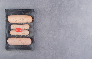 Tomato and spicy sausage on the board, on the marble background