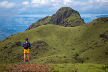 Naklejka premium woman in hiking boots watching the view from the top of the mountain in costa rica, cerro pelado; brave hiker girl enjoying the view from the top after a hard hike