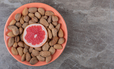 Grapefruit and almonds on the plate on the marble background