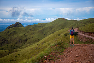 Obraz premium woman in hiking boots watching the view from the top of the mountain in costa rica, cerro pelado; brave hiker girl enjoying the view from the top after a hard hike