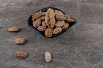 flavorful almonds in the bowl, on the marble background