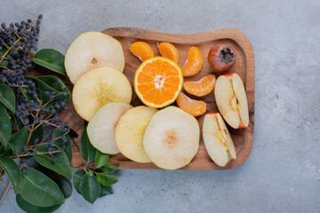 Sliced fruits bundled on a wooden board on marble background