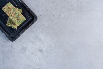 Green Turkish delights on a small board on marble background