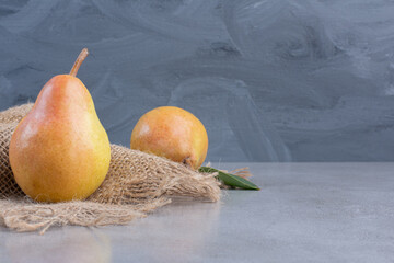 Succulent pears and a piece of cloth on marble background