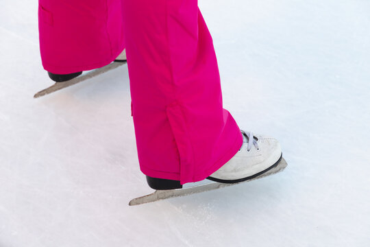 Legs of a girl on skates on a white ice rink