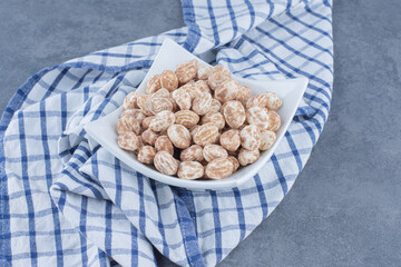 Delectable cinnamon candies in the plate, on the marble background