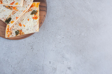 Pizza slices on a wooden board on marble background