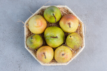 Small bundle of assorted pears in a white basket on marble background