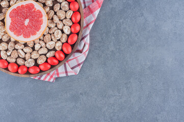 Tray full of cookies and gums with grapefruit in the middle, on the marble background