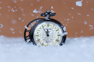 Vintage pocket watch close-up on the snow. Five minutes to midnight.