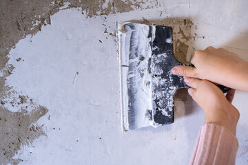 Children's hands work with a spatula. Alignment of walls, finishing works. Applying putty