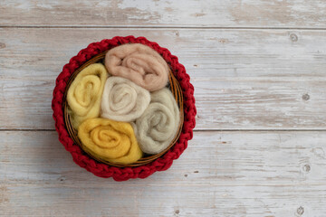 handmade red basket crochet with wool for felting and hobby on wooden background.