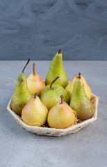 Small bundle of assorted pears in a white basket on marble background