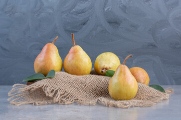 Pears on a board covered with a piece of cloth on marble background