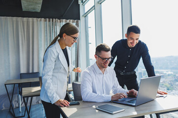 Group of business people in casual clothes talking to each other in office and using gadgets while working on business startup in modern workspace