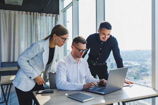 Group of business people in casual clothes talking to each other in office and using gadgets while working on business startup in modern workspace