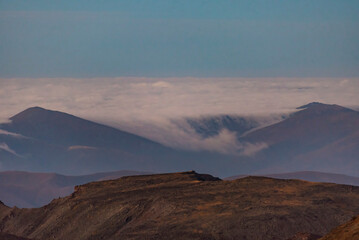 Naklejka premium Panoramic view form mountains peak on the fog and clouds. Sunrise landscape. 