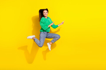Full length photo of crazy active person jump indicate fingers empty space isolated on yellow color background