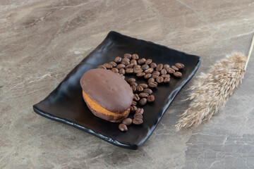 Chocolate cupcake on black plate with coffee beans