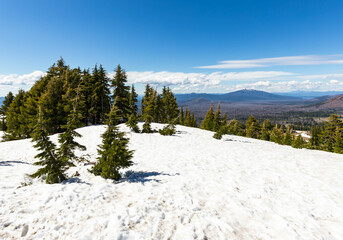 Snow covered hills in summer at Crater Lake area in Oregon, on a blue sky afternoon.