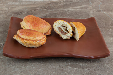 Homemade pastry with meat on brown plate