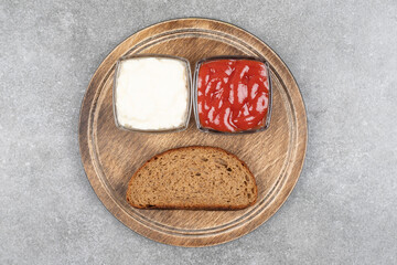 Black bread slice, ketchup and mayonnaise on wooden board