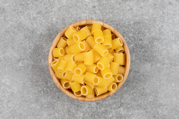 Pile of raw macaroni in wooden bowl