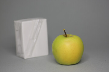 tetrahedral package of juice and an apple isolated on gray background