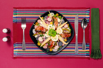 Top view of a plate with vegetables and cold meats, on a textile background typical of the indigenous peoples of Mesoamerica. - obrazy, fototapety, plakaty