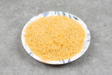 Pile of uncooked macaroni on colorful plate