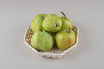 Bundle of pears in a white basket on marble background