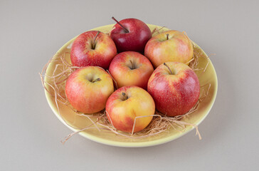 Delectable apples and straw in a bowl on marble background