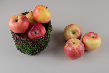 Fresh apples in and next to a bowl on marble background