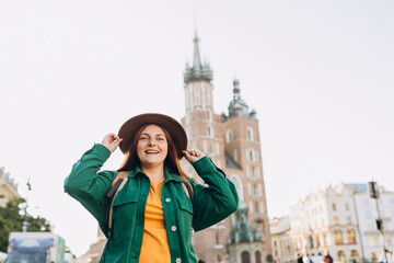 Obraz premium Famous cathedral in sun light, Tourist happy woman on Market Square in Krakow, Traveling Europe in autumn. St. Marys Basilica