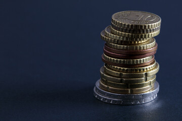 Stack of coins on black table close up. Finance, business, economy concept with copy space. Soft focus