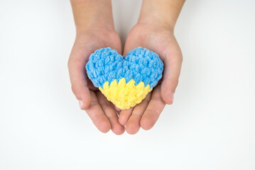 High angle view of children's hands holding a heart painted in the Ukrainian flag, hearts in hands on a white background. Patriotic concept.