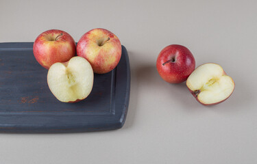 Sliced and whole apples on and next to a board on marble background
