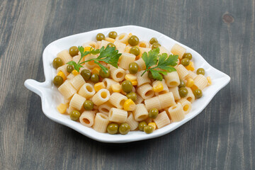 Delicious macaroni with peas and greens on a wooden table