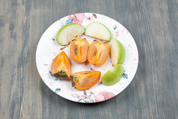 Sliced delicious persimmon with sliced green apple