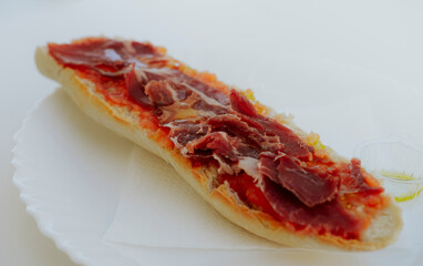 Breakfast toast of cured ham with the bread served on a white plate on a white table. Close-up