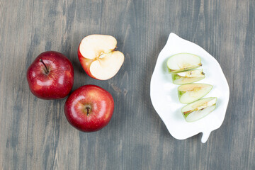 Green and red apples sliced isolated on a white plate