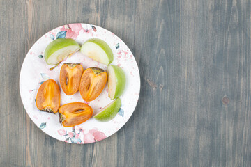 Sliced delicious persimmon with sliced green apple