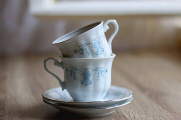 Two stacked vintage porcelain cups on the table. Selective focus.