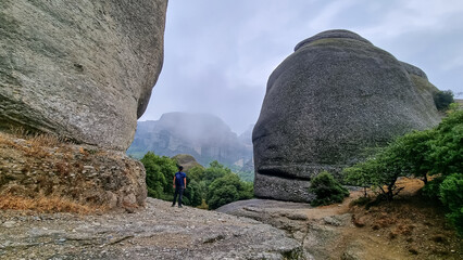 Active man with backpack standing under massive rock formation pinnacles near village Kastraki on...