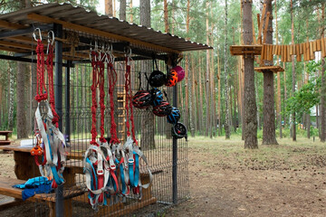 Children's rope park in a pine forest. Coach's position. Protective helmets and safety ropes hang...