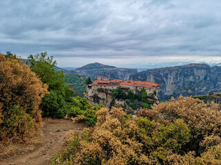 Obraz premium Scenic view of Holy Monastery of Varlaam on cloudy foggy day, Kalambaka, Meteora, Thessaly, Greece, Europe. Rock formations overgrown with green moss creating moody atmosphere. UNESCO World Heritage