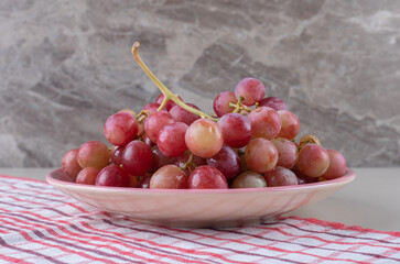 Platter of grapes on a towel on marble background